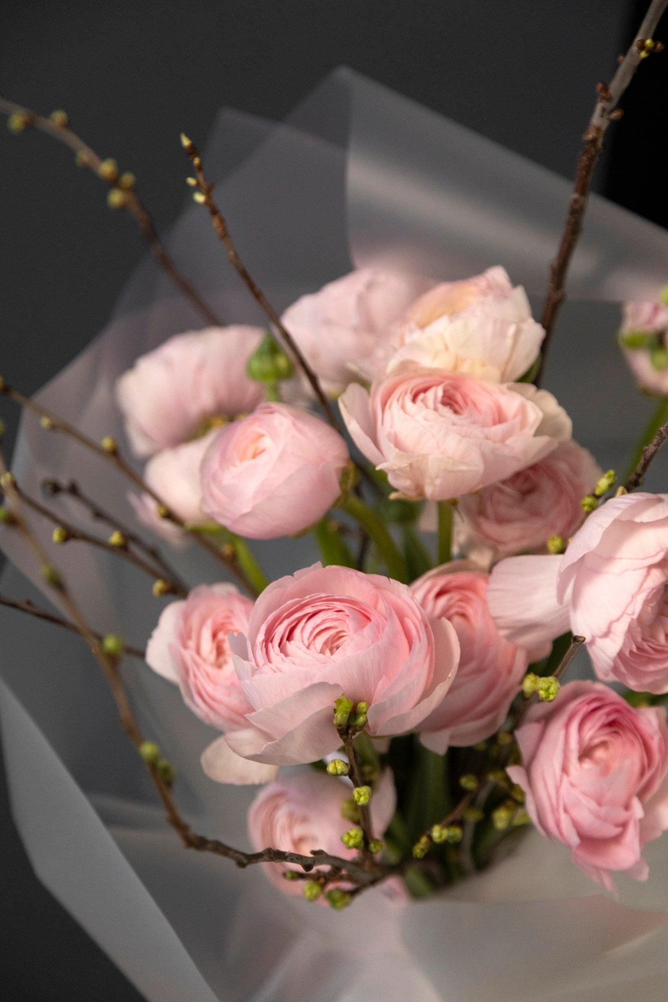 Close-up of pink ranunculus blooms and cherry branches in the Spring Blush bouquet